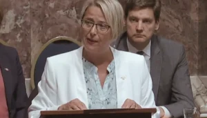 MLA Judy Darcy stands at a podium in BC Legislature to give a speech about the work of the New West Hospice Society